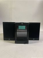 Front view of main unit flanked by both speakers, power on displaying FM 99.9