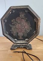 Front view showing octagonal frame, floral cloth grille, base, and attached wire