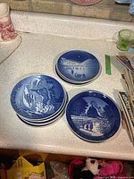 Two stacks of nine total blue porcelain collector plates on countertop
