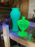 Vase and covered candy dish on shelf under ambient light
