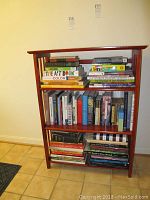 Front view of one collapsible wooden bookcase loaded with books, showing the style and condition including minor wear.