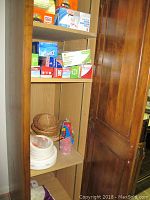 Shelf with various boxes of Ziploc bags, paper plates, plastic cups, and small baskets.