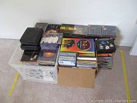 Large variety of CDs stacked in two containers and laid out, including some classic rock and classical music albums.