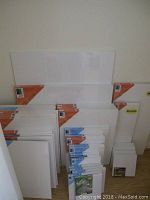 Overview of multiple unopened pre-stretched canvases leaning against wall