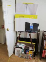 Wooden easel with large art paper pads, watercolor paper, portfolio case and various art supplies below