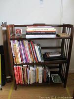 Dark wood bookshelf shown from front holding books and knick-knacks