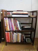 Wooden bookshelf holding art and anatomy books, arranged in three rows.