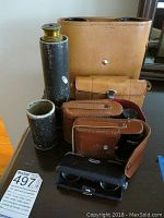 Group photo showing all binoculars and the telescope with their carrying cases on a table.