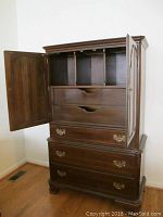 Full view of the Ethan Allen wooden armoire with one door open showing interior compartments, drawers, and cubbies.