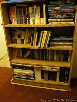 Four-shelf wooden bookshelf filled with various history, aviation, military, and DIY books.