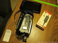 Sony Handycam, RCA TV, and Canon AC adapter kit displayed on wooden table.
