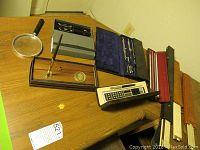 Wide angle photo showing drafting tools, fountain pen set, calculator in box, magnifying glass, desk pen with Johns Hopkins University emblem.