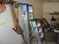 Photo showing two aluminum step ladders side by side in a garage setting with other tools