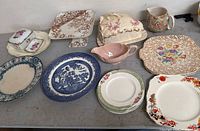 Overview of assorted porcelain jug, plates, platters, cake plate and covered dish on table