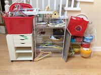 Wide shot of all items showing white wire shelving units, IKEA cabinet, red Rubbermaid tub with hangers, box and napkins.