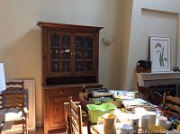 Full view of the country style wooden buffet and hutch in a dining room setting, showing the upper glass doors and lower drawer and cabinet storage.