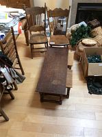Overall view showing rectangular wood nesting coffee tables with two smaller tables inside and two wooden pressed back chairs behind the tables.