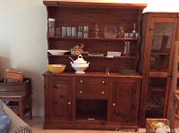 Full view of the country style wood buffet and hutch with items on display shelves and top surface.