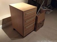 IKEA filing cabinet with three drawers visible against a wall, closed drawers, on castors, light wood grain finish
