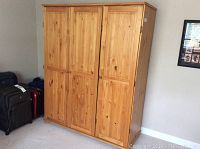 Photo of closed IKEA pine wardrobe showing paneled doors and natural wood finish.