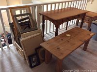 Photo showing wooden desk with two drawers, coffee table with rustic finish, and wicker basket holding art frames