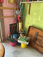 Corner of garage showing long-handled tools, buckets, umbrella, hand tools in tray