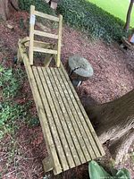 Overall view of wooden slatted lounger under tree