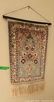 Full view of tapestry on wall showing design, rod and cord