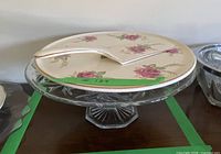 Porcelain plate with rose pattern sitting on glass pedestal stand