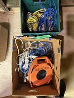 Box containing orange H.B. McLean cable reel, extension cords, power strips, and green crate of ropes