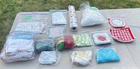 Full lot overview on table showing all bagged linens, crocheted items, yarn balls and liner roll