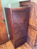 Full view of tall cherry veneer filing cabinet showing four drawers and lock