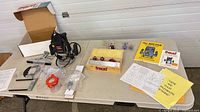 Full lot overview on table showing router, bit set, manuals, accessories