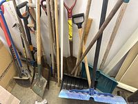 Group of shovels, snow pusher, cultivator, mattock visible