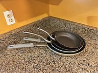 Three nested Calphalon frying pans showing sizes and handles