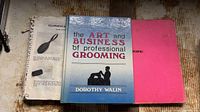 Three grooming references laid out: comb-bound manual, hardcover Walin book, pink manual