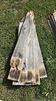 Stack of weathered pine boards on grass showing overall condition