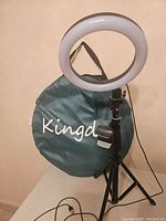 Ring light mounted on tripod with phone holder, USB cable visible