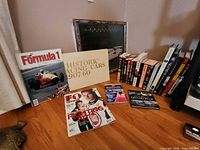 Lot overview showing poster, large books, magazine, stack of racing books and figurines