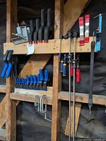 Overall view showing multiple blue quick-grip clamps, black spring clamps, long Bessey bar clamps and two C-clamps