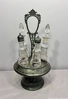 Full view of silver plate stand with five glass bottles