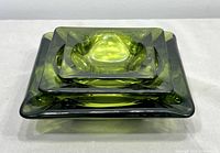 Three nested emerald green glass ashtrays stacked