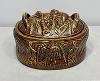 Front view of lidded casserole showing wildlife relief and glaze