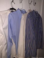 Four dress shirts hanging: white, light blue, beige, blue/tan striped