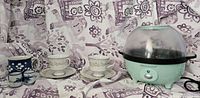 Popcorn machine, two teacups with saucers, blue-and-white mug and cups