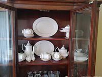 Cabinet view showing platters, teapot, sugar bowl, creamer, cups, bowls