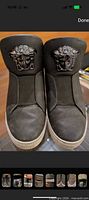 Front view showing both sneakers, leather texture, Medusa head plaques