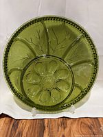 Full view of green glass deviled egg tray showing 8 wells and center section
