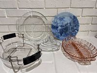 Group shot of all five pieces: pink relish dish, blue scenic plate, clear pie plate, clear baking dish in metal carrier, clear ridged trivet