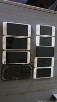 Nine iPhones laid out in two columns showing cracked screens